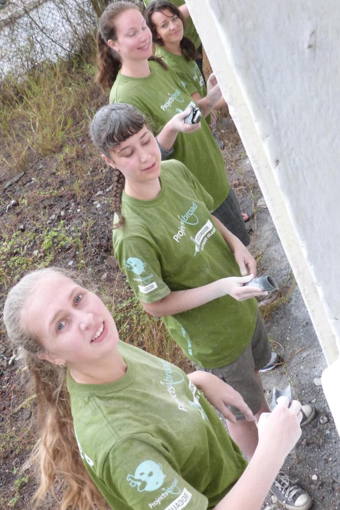 Volunteers in Ecuador helping to paint a wall with Projects Abroad Ecuador volunteer group painting a wall